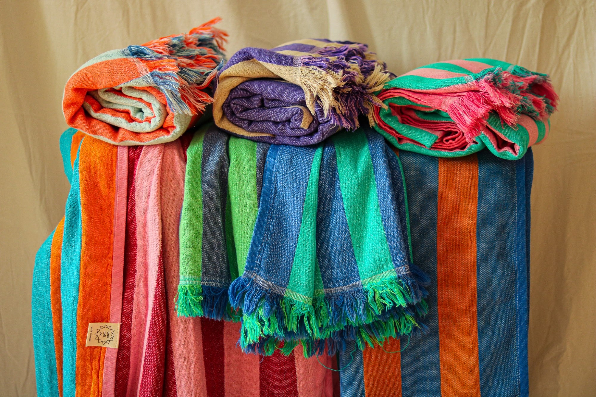 Colorful striped Turkish towels displayed on a stand against a beige background